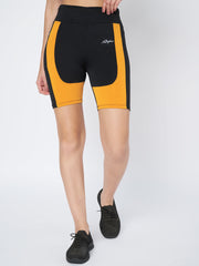 Front view of Waylene's high-waist black and orange sports shorts, modeled with a black top and sneakers, showcasing the shorts' design and side panel detailing.