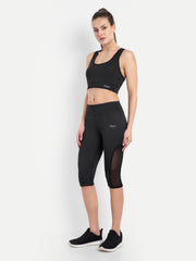 Waylene's black Capri and sports bra tracksuit set for women, perfect for yoga and gym. Model stands confidently with hands on hips, showcasing the mesh panel design on Capri and fitted sports bra.