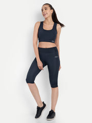 ALT text: Model leaning slightly forward in Waylene's navy blue capri tights and sports bra, demonstrating the flexibility and comfort of the fabric.
