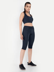 ALT text: Model standing erect with hands on hips in Waylene's navy blue capri tights and sports bra, emphasizing the high waist and snug fit.