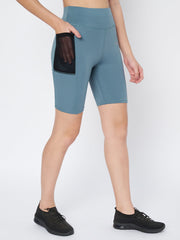 Woman inserting a smartphone into the side pocket of Waylene's light blue high-waist cycling shorts, demonstrating practicality and comfort, matched with black sneakers.