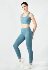 Waylene's airforce blue women's track suit, model posing with one leg slightly raised, wearing a form-fitting tank top and leggings, completed with white sneakers.