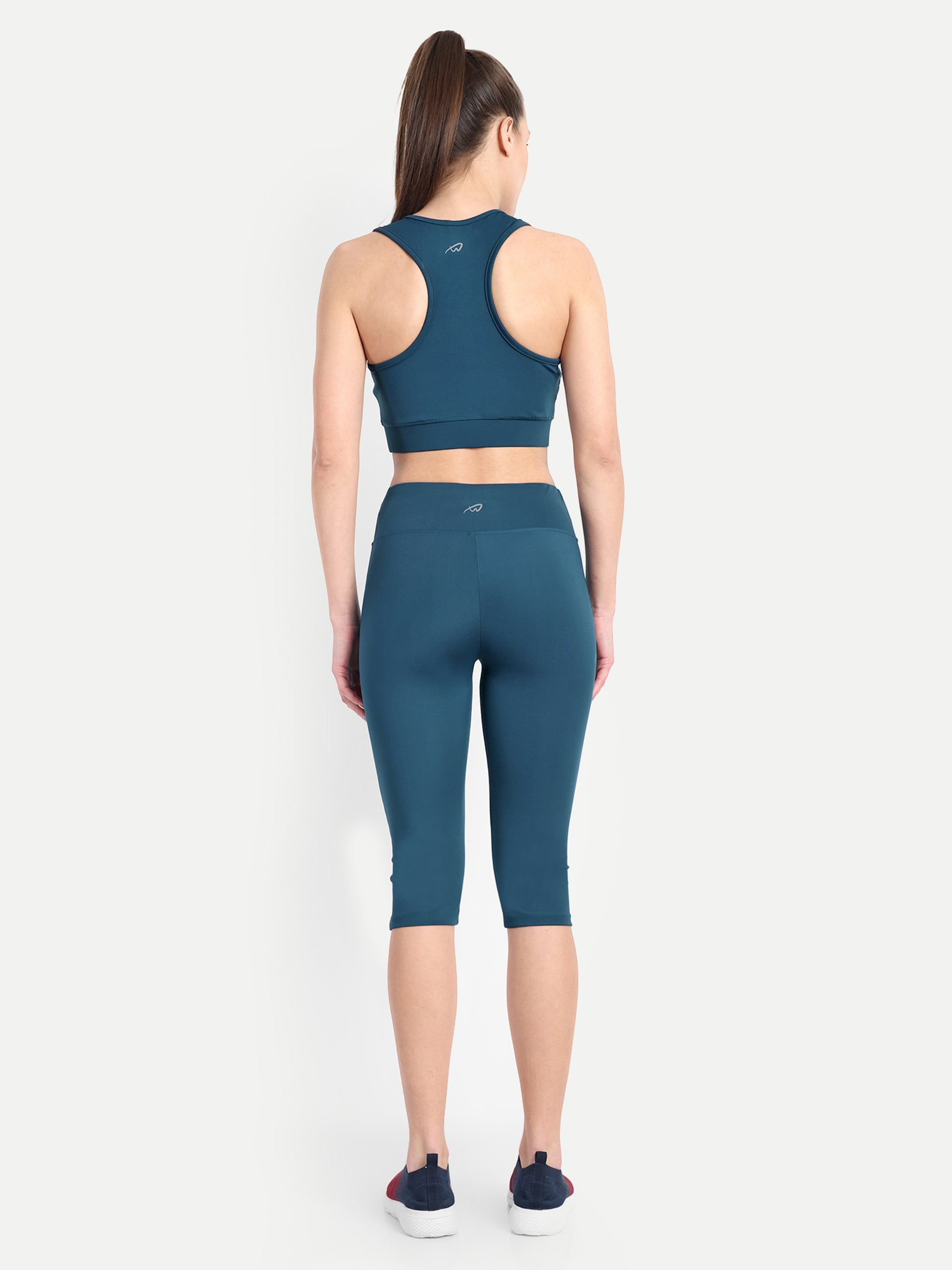 Rear view of a model in Waylene's teal blue capri and sports bra set, focusing on the back coverage and waistband fit, demonstrating the supportive design.